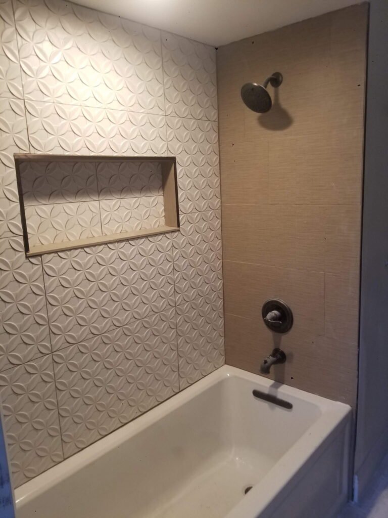 Custom tiled shower with textured white wall tile and recessed niche.