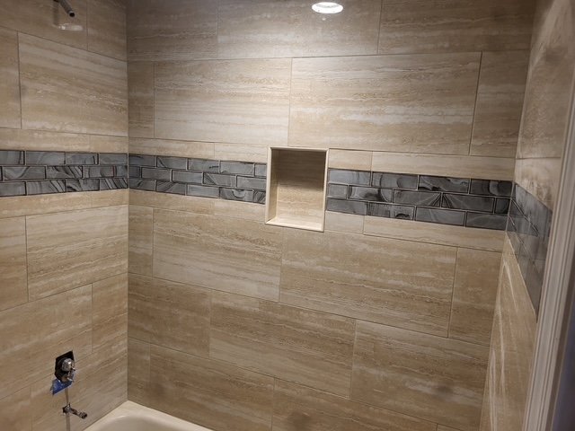 Shower wall tile with mosaic accent and recessed niche.