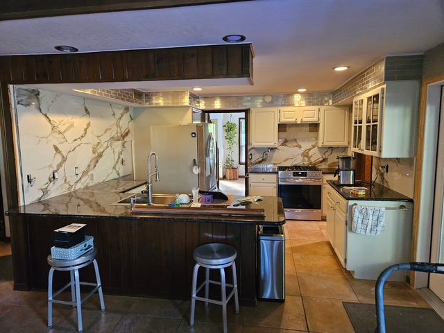 Kitchen remodel with marble-look backsplash and dark island.